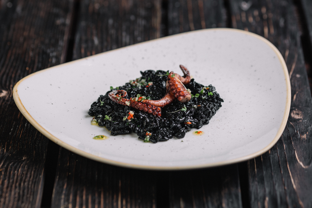 Black,risotto,with,cuttlefish,ink,and,octopus,tentacles,on,irregular
